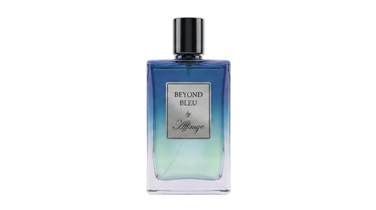 A rectangular glass perfume bottle with a black cap, featuring a blue-to-green gradient design and a silver label that reads 'BEYOND BLEU by Migeau'.
